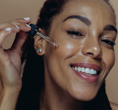 Black woman applying serum to her skin